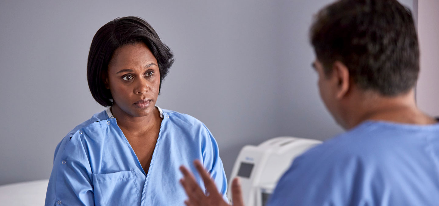 Woman patient talking to healthcare professional with image scans at the back