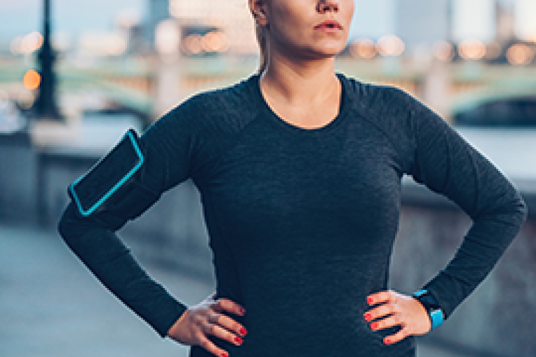 Woman in black workout attire with hands on hips outdoors