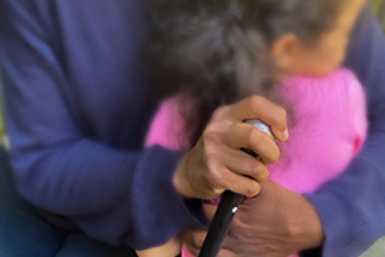 Upclose of black grandmother holding cane and hugging young girl