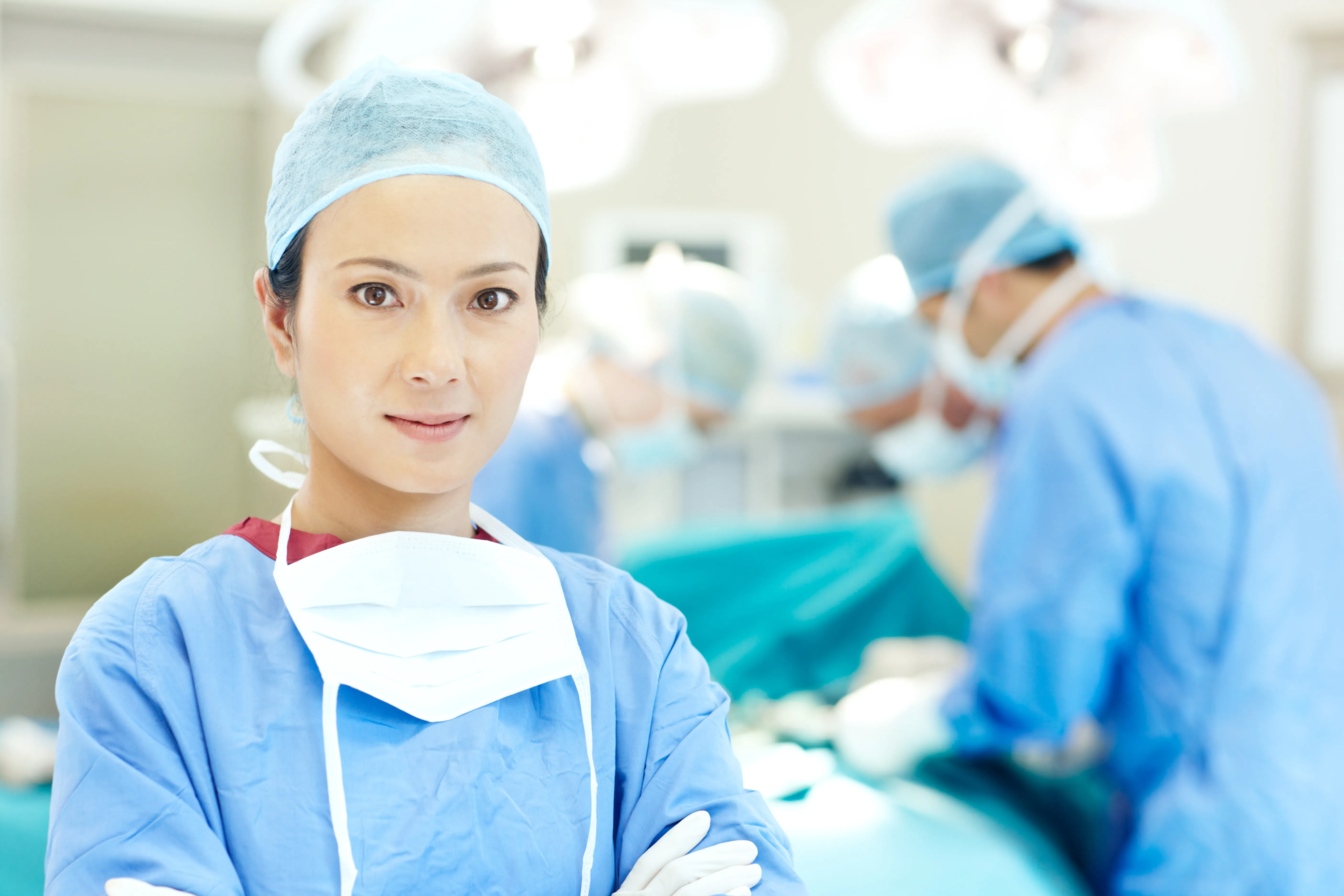 A female healthcare professional looking into the camera in a surgical room setting