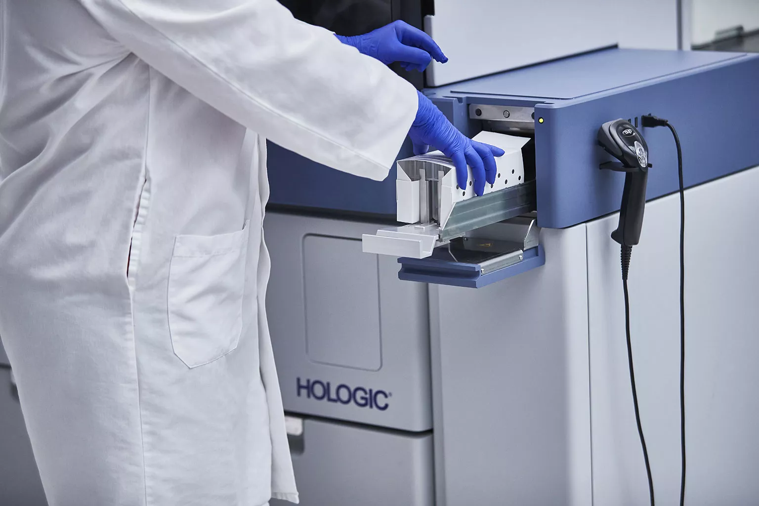 Lab technician placing tray of tubes in Panther system in lab setting.