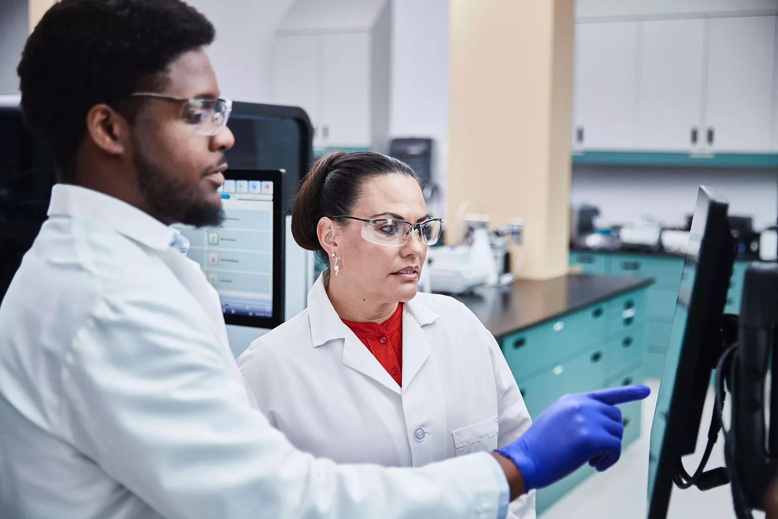 Lab technician looking and pointing to monitor screen in lab setting