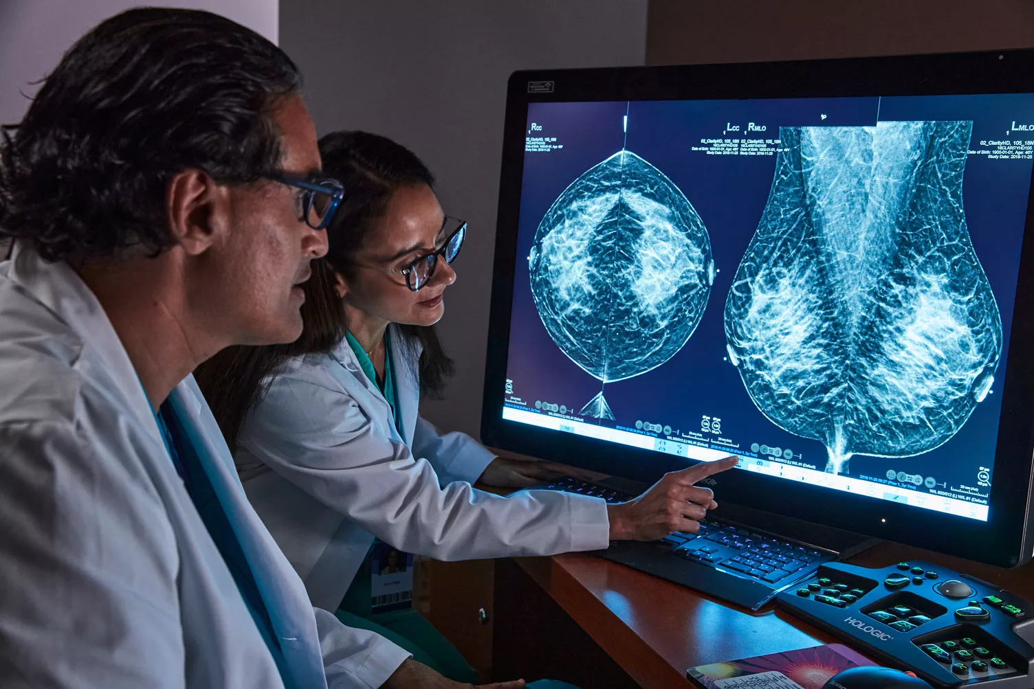Healthcare professional pointing to breast scan image on monitor