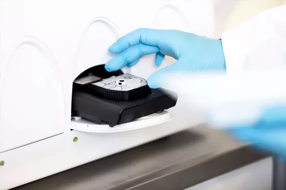 Lab technician inserting cartridge into a system in a lab