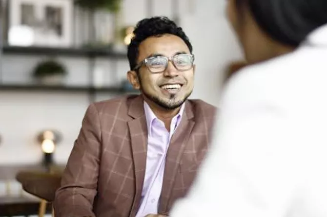 Hispanic man smiles and speaks with woman in an office setting