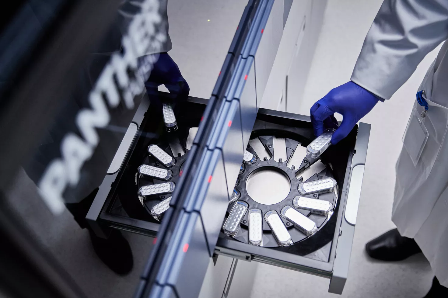 Laboratory technician loading a cartridge onto the Panther Fusion instrument