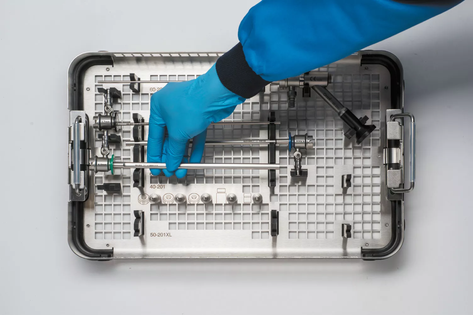 Gloved hand working medical tray on table.