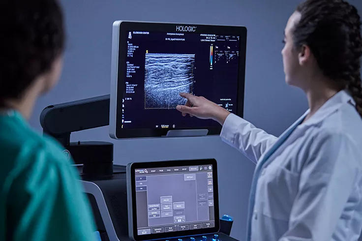 Healthcare professional pointing at monitor and talking to patient