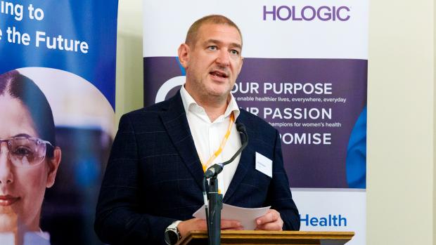 Man at podium providing opening speech with two vertical banners behind him