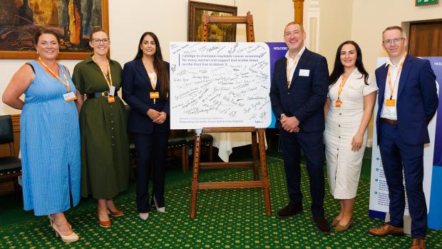 Attendee's standing next to a pledge board with signatures at the launch event.