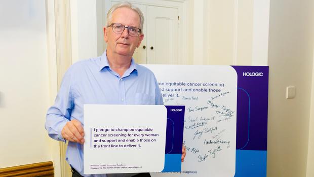 Man in blue suit holding pledge board