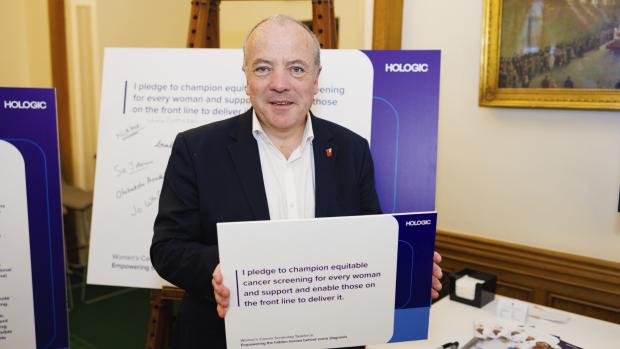Man in suit signing large pledge board
